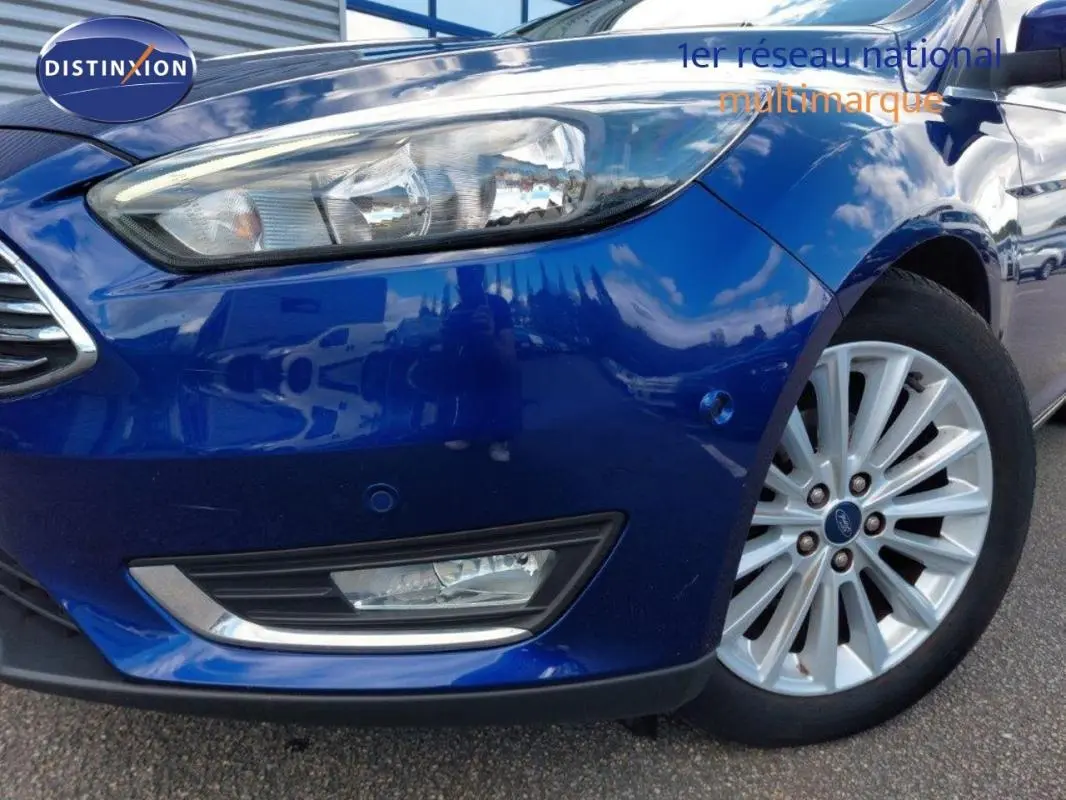 Gros plan sur l'avant droit bleu foncé d'une Ford Focus SW 2018 avec jante alliage 17 pouces et phare allumé.