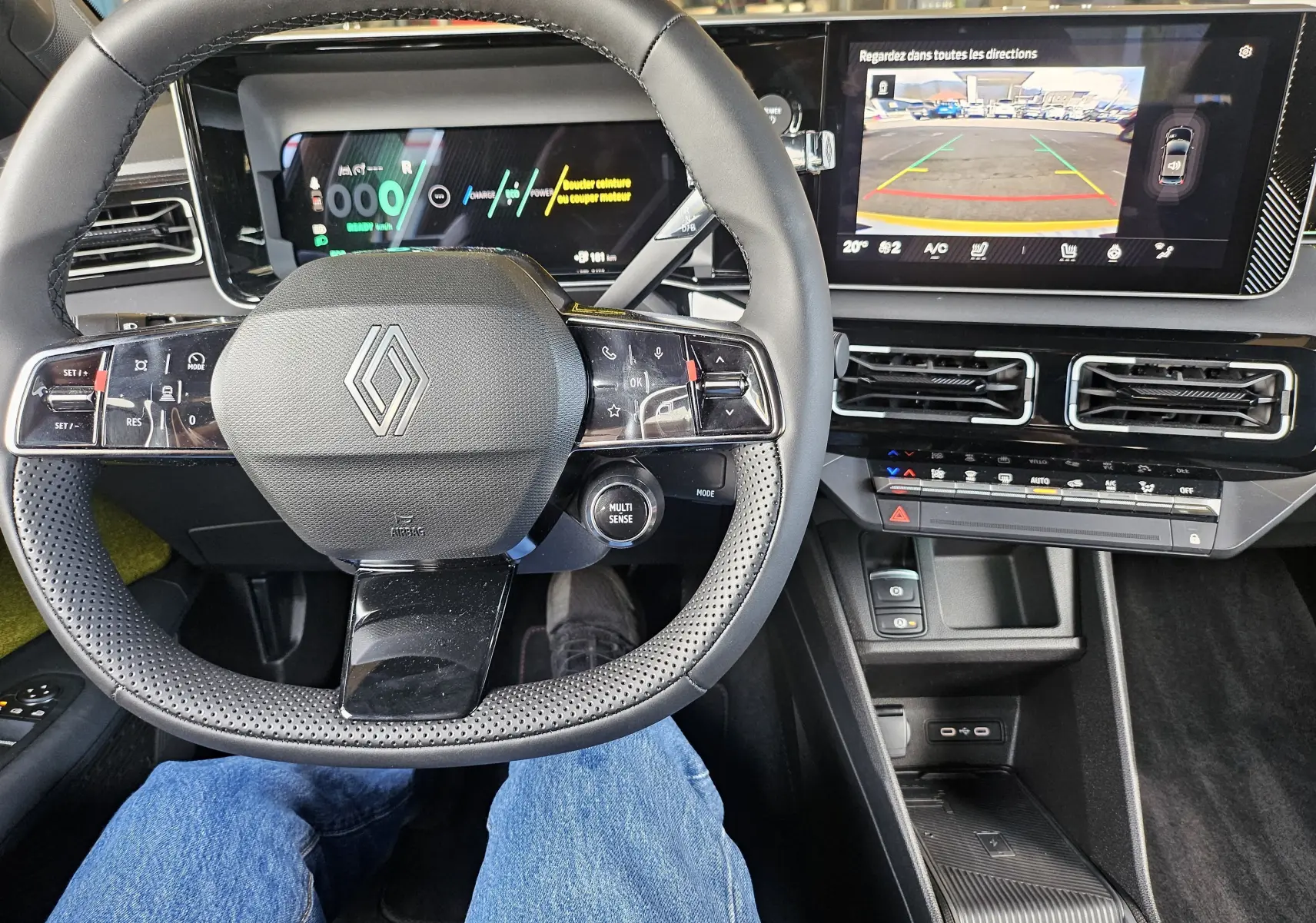 Vue intérieure centrée sur le volant Renault R5 électrique 2025, avec tableau de bord numérique et écran multimédia affichant la caméra de recul.