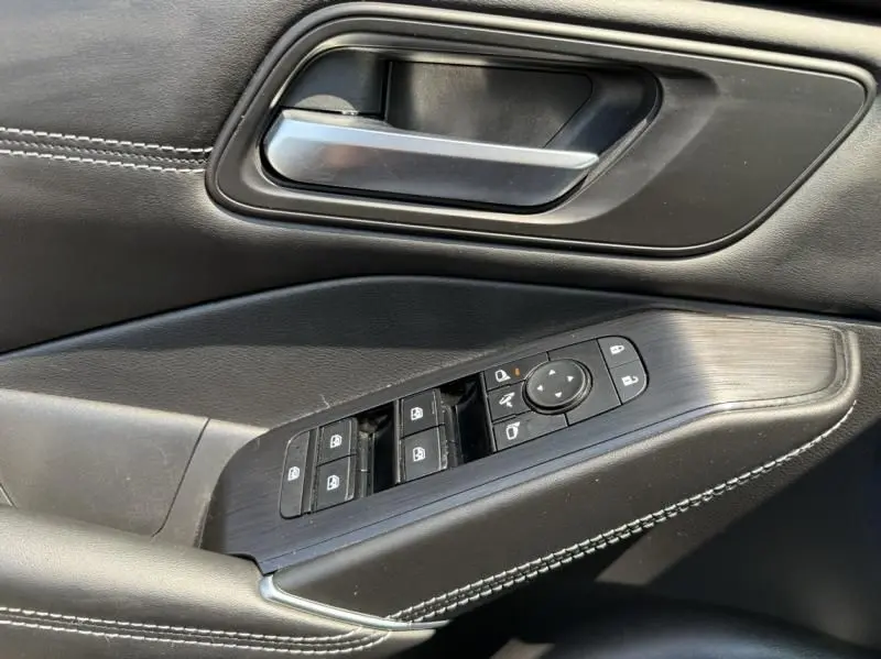Détail de la porte côté conducteur du Nissan Qashqai noir 2023 montrant les commandes des vitres et le bouton de réglage des rétroviseurs.