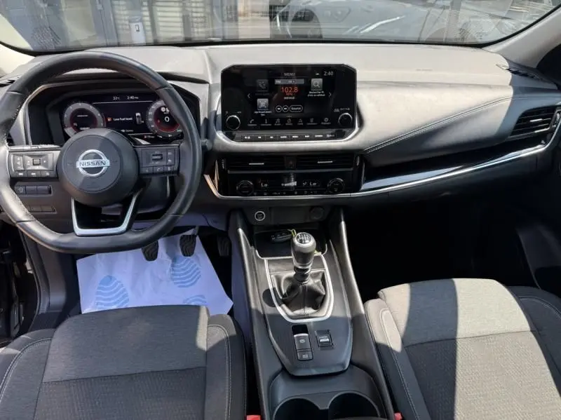 Intérieur du Nissan Qashqai 2023 noir, vue frontale sur le tableau de bord avec écran tactile et boîte manuelle.