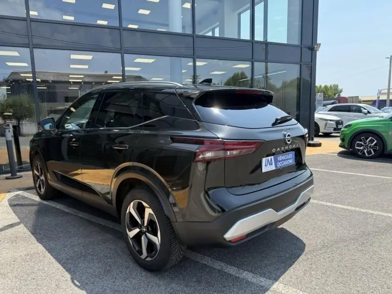 Nissan Qashqai 2023 noir en 3/4 arrière droit, avec feux arrière étirés et jantes alliage distinctives.