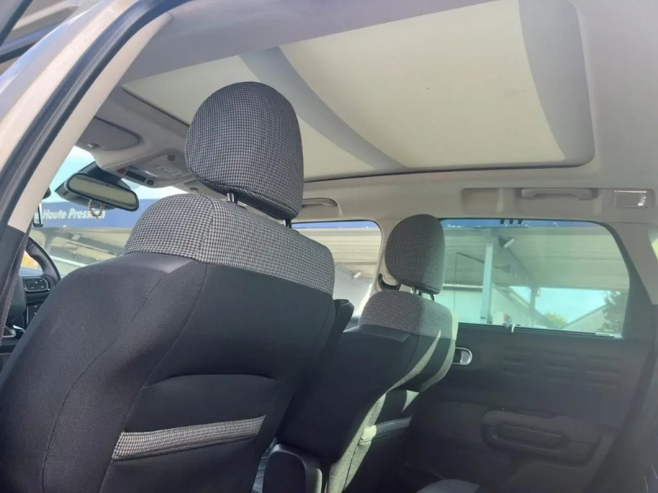 Vue intérieure arrière du Citroën C3 Aircross 2019 avec sièges tissu noir et gris et toit ouvrant panoramique en verre.