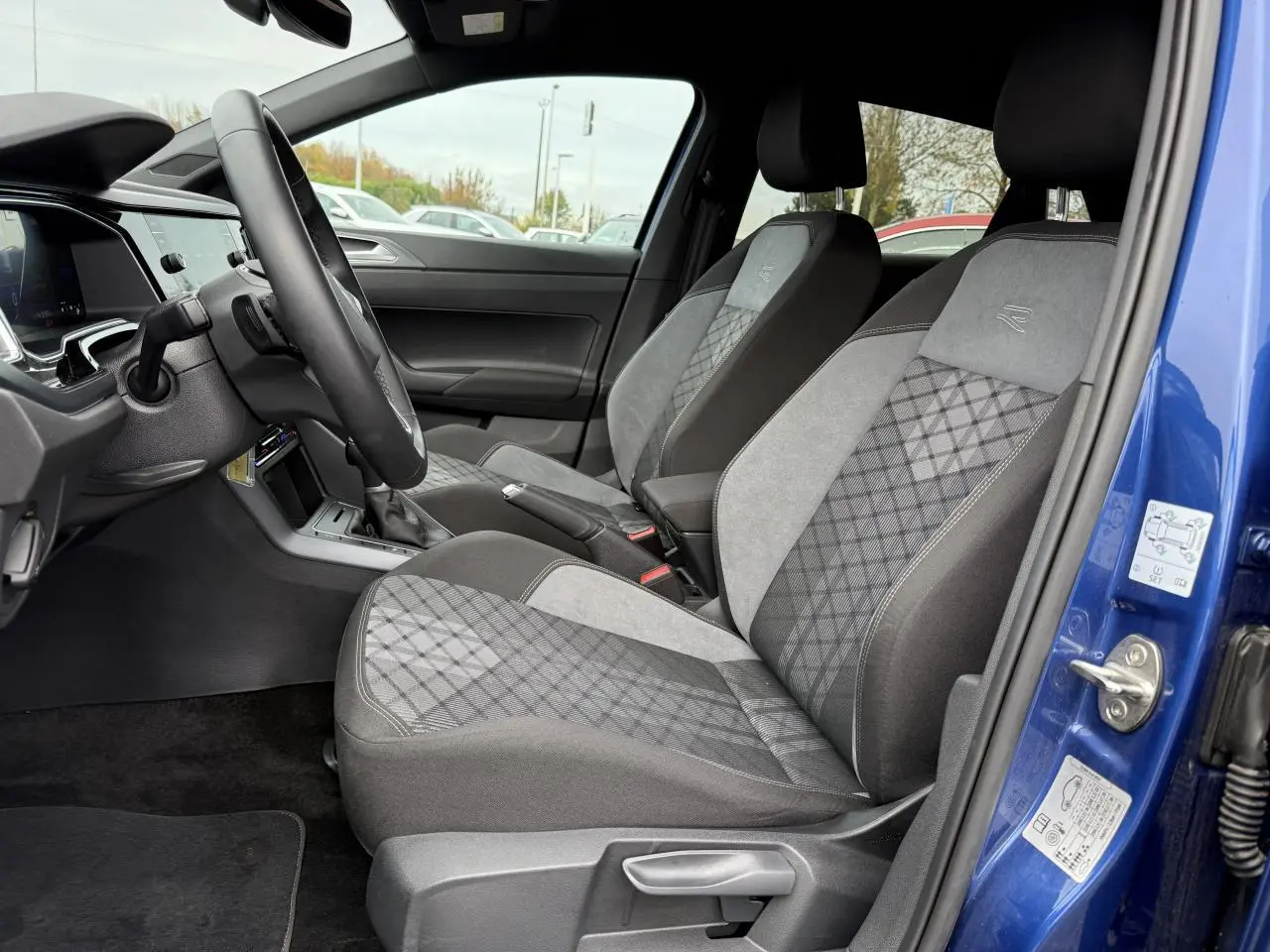 Intérieur côté conducteur d'une Volkswagen Polo bleu récif, sièges R-Line en tissu gris à motifs losanges.