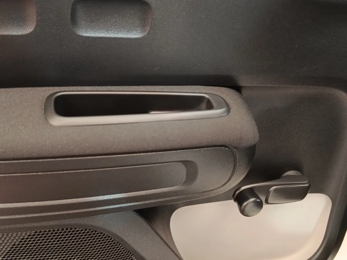 Détail de la poignée intérieure et manivelle de lève-vitre côté droit d’une Citroën C3 blanche 2020.
