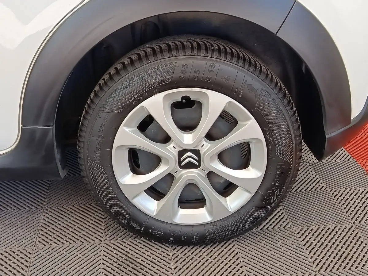 Gros plan sur la roue arrière droite d'une Citroën C3 blanche avec jante alliage et logo Citroën central.