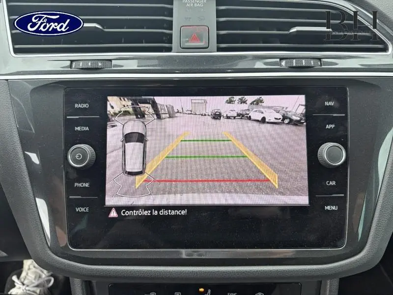 Écran tactile central montrant la caméra de recul d’un Volkswagen Tiguan gris dauphin, vue intérieure avant.