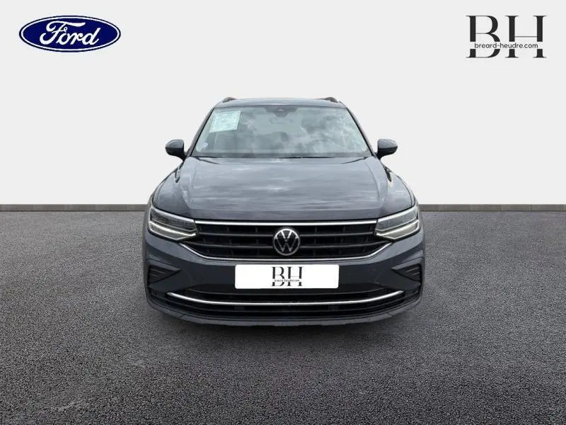 Vue de face d'un Volkswagen Tiguan gris dauphin métallisé avec calandre noire et phares LED allumés.