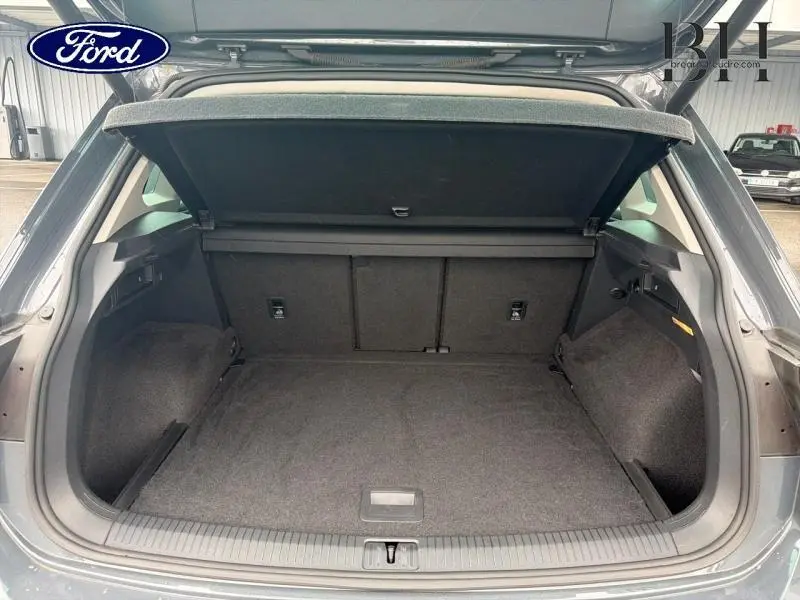 Vue du coffre ouvert du Volkswagen Tiguan gris dauphin métallisé, montrant l'espace de chargement et la tablette cache-bagages.
