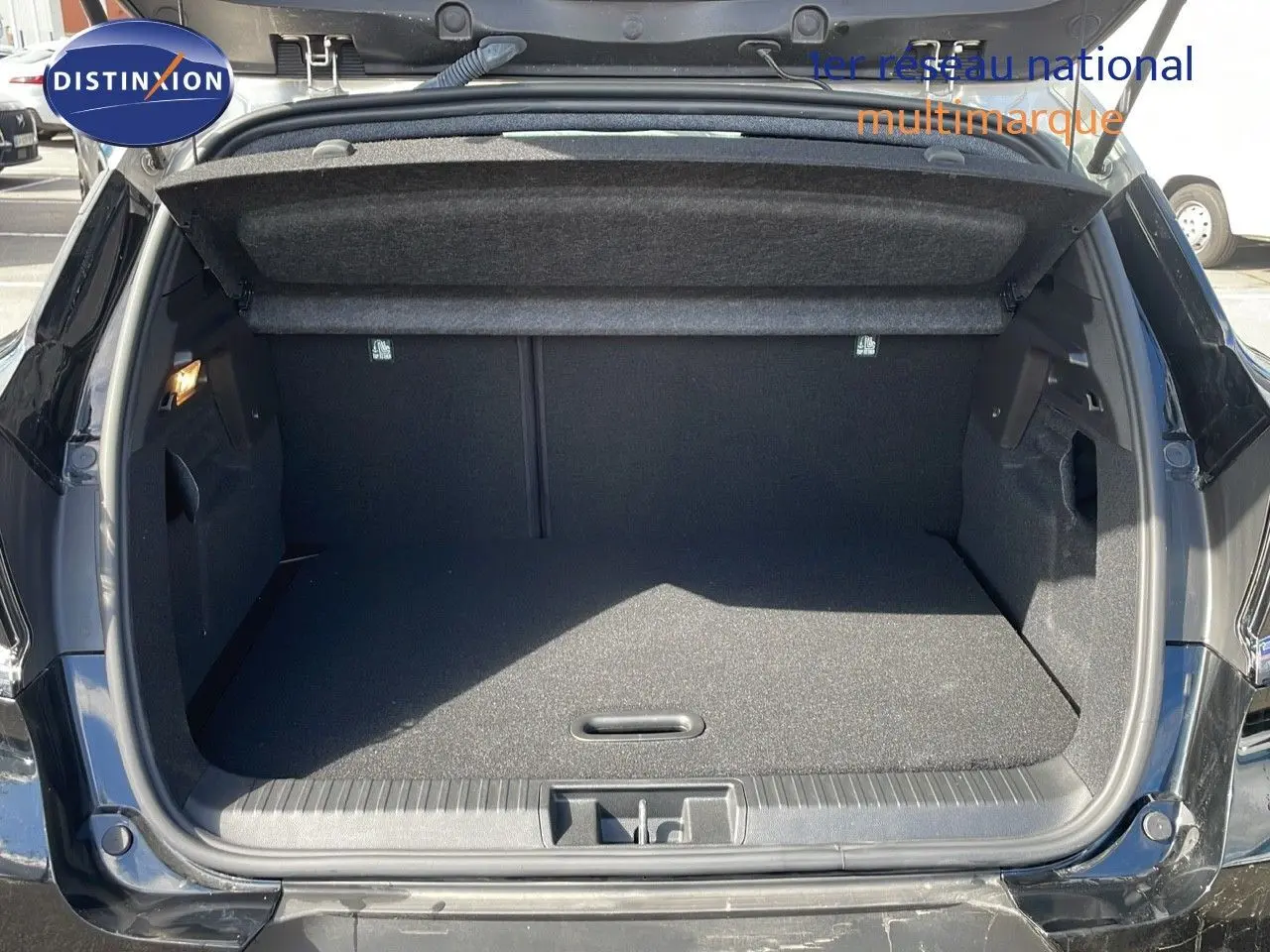 Coffre ouvert en vue arrière d’un Renault Captur 2025 noir étoile métal avec toit gris, intérieur de coffre spacieux et propre.
