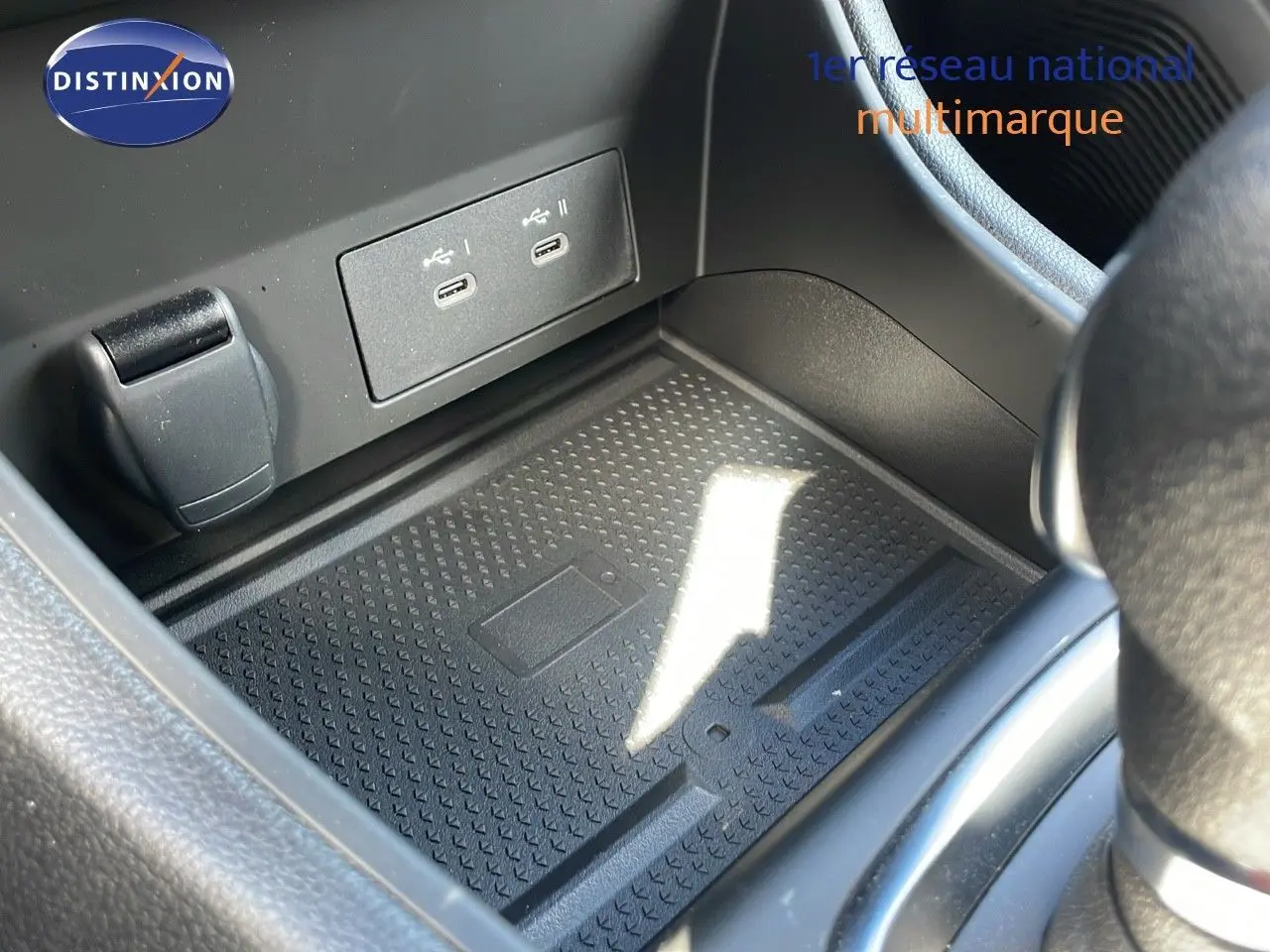 Gros plan sur la console centrale du Renault Captur 2025, montrant un espace de rangement avec ports USB et prise 12V.