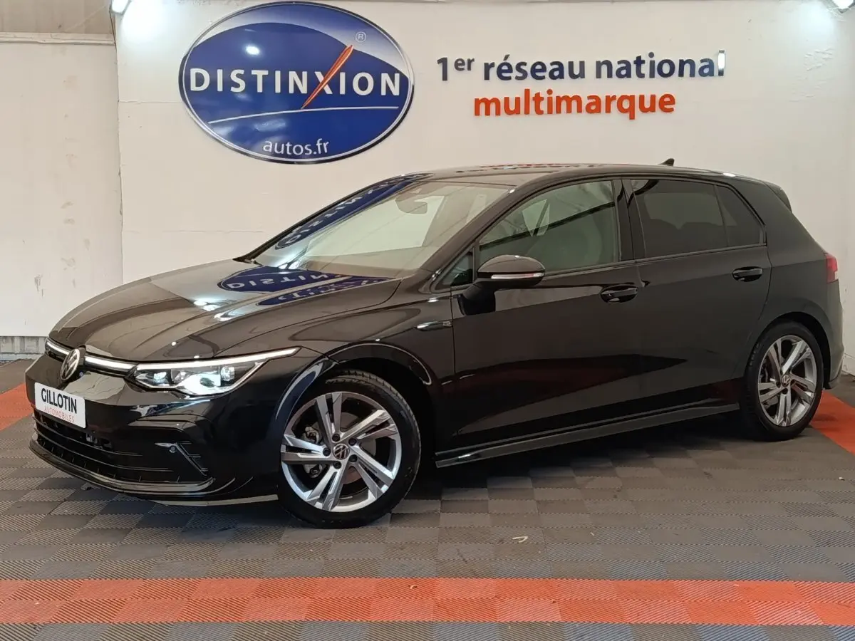 Volkswagen Golf 1.5 eTSI R-Line noire vue de profil droit en intérieur avec jantes alliage et phares allumés.