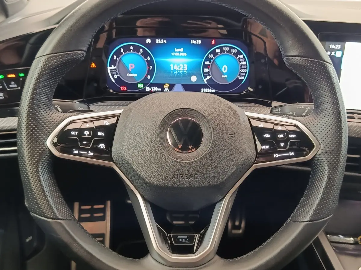 Gros plan sur le volant cuir multifonctions de la Volkswagen Golf 1.5 eTSI R-Line avec tableau de bord numérique lumineux.