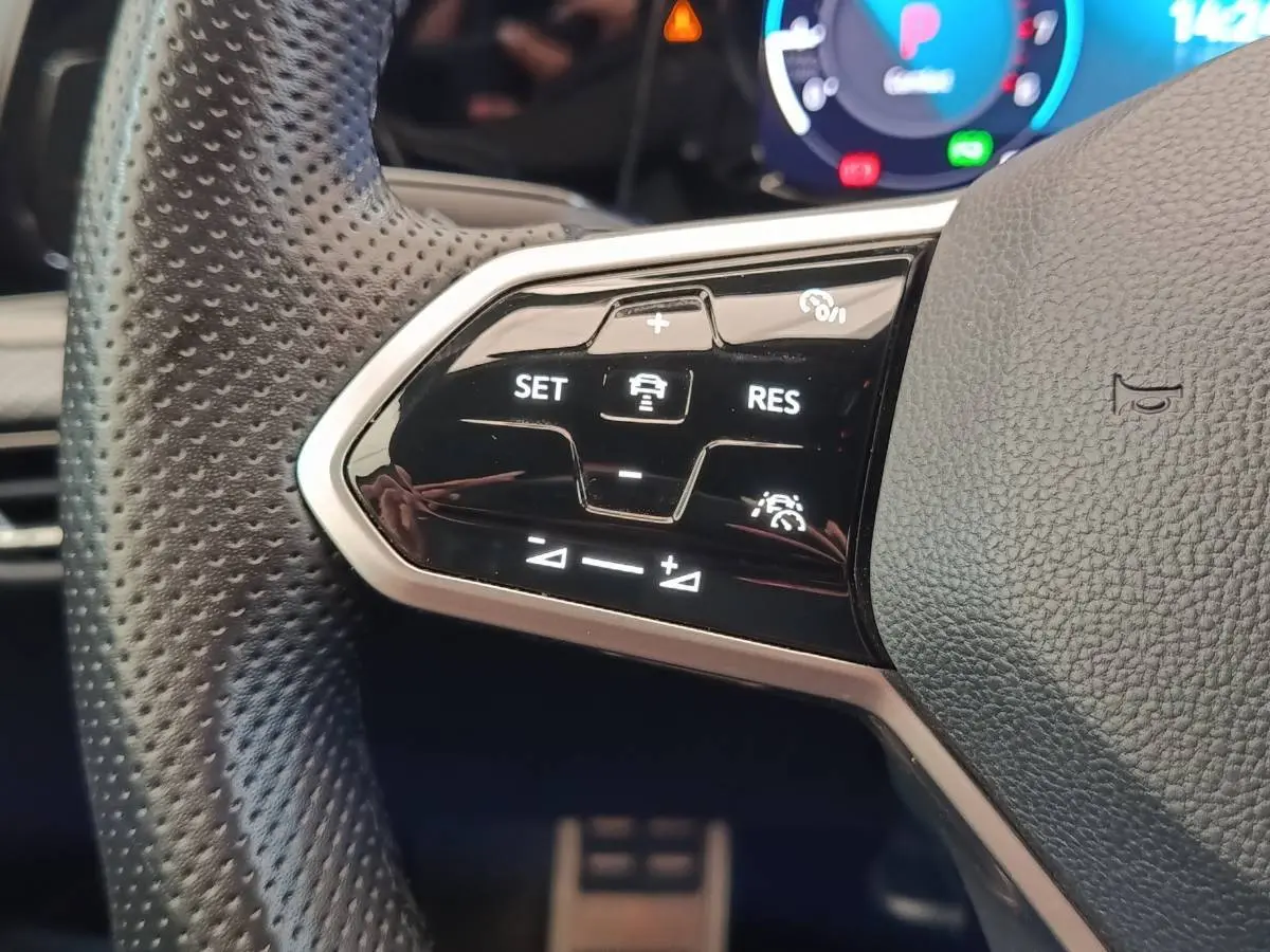 Gros plan sur les commandes du régulateur de vitesse au volant cuir noir de la Volkswagen Golf 1.5 eTSI R-Line 2021.