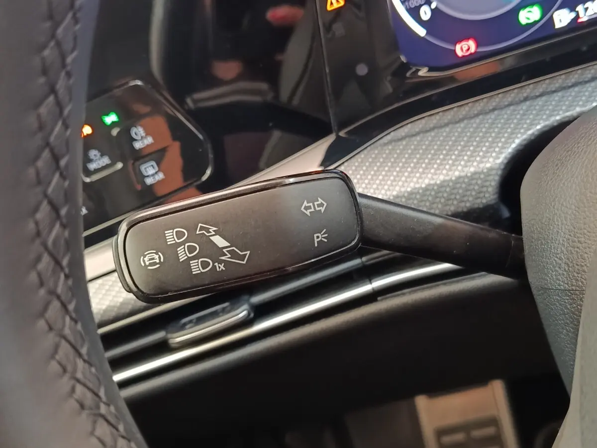 Gros plan sur la manette de clignotant et feux dans l’habitacle d’une Volkswagen Golf noire, tableau de bord en arrière-plan.