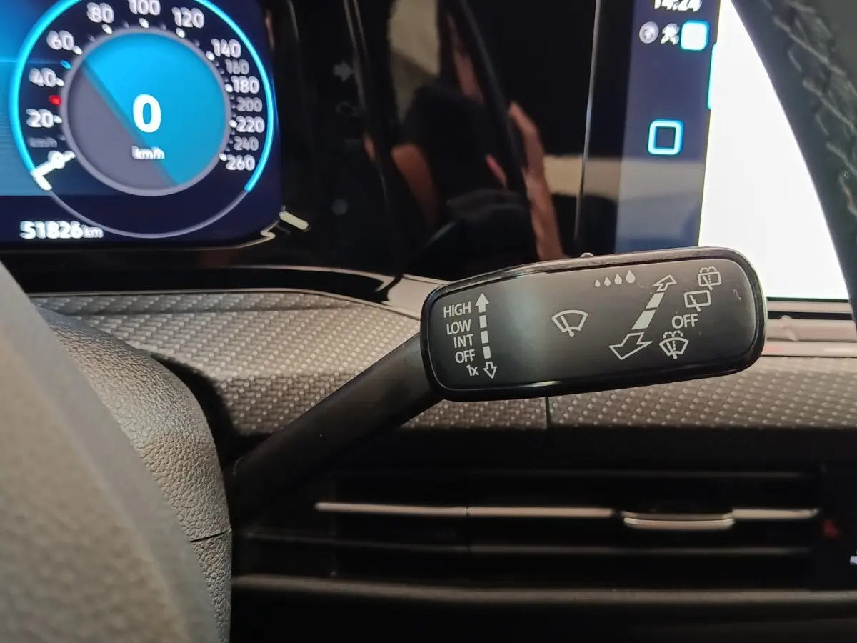 Gros plan sur la commande d’essuie-glace à gauche du volant dans l’habitacle noir d’une Volkswagen Golf 1.5 eTSI 2021.