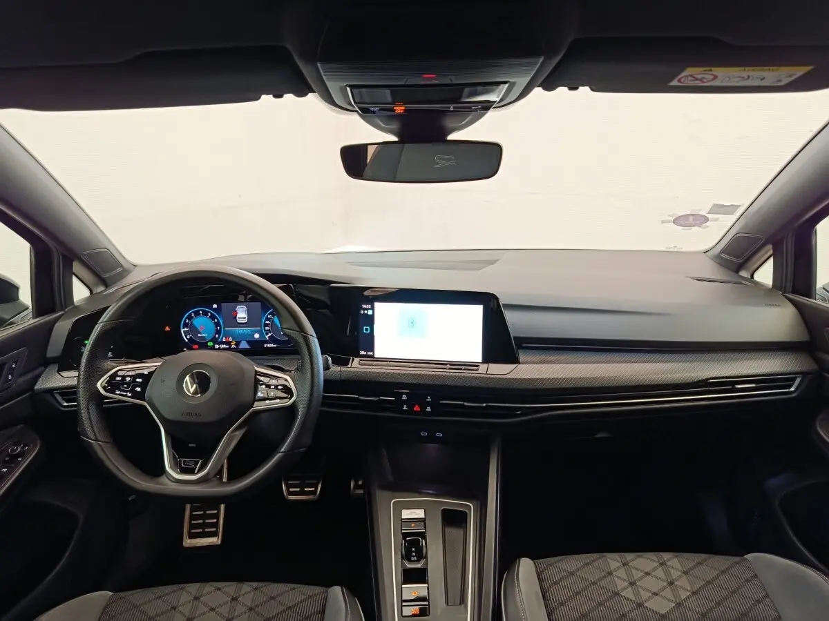 Vue intérieure avant de la Volkswagen Golf 1.5 eTSI R-Line 2021, tableau de bord noir avec écran tactile et volant cuir multifonctions.