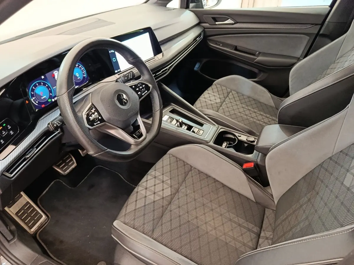 Vue intérieure côté conducteur de la Volkswagen Golf 1.5 eTSI R-Line 2021, sièges gris à motif géométrique et tableau de bord digital.