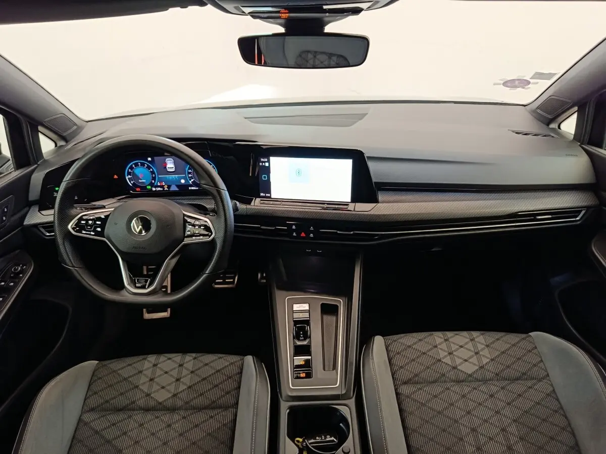 Vue intérieure avant de la Volkswagen Golf 1.5 eTSI R-Line 2021, tableau de bord moderne avec écran tactile et volant cuir.