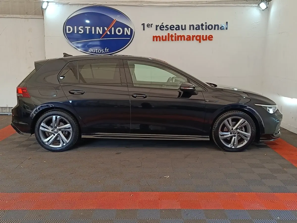 Volkswagen Golf 1.5 eTSI R-Line noire vue de profil côté gauche dans un showroom intérieur.