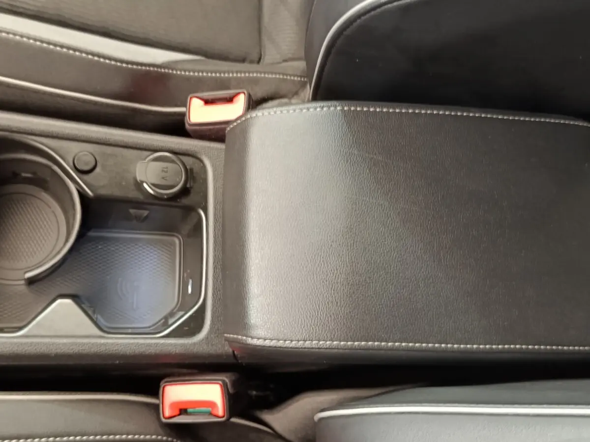 Vue rapprochée de la console centrale noire avec accoudoir cuir et zone de recharge sans fil dans une Volkswagen Golf 2021.