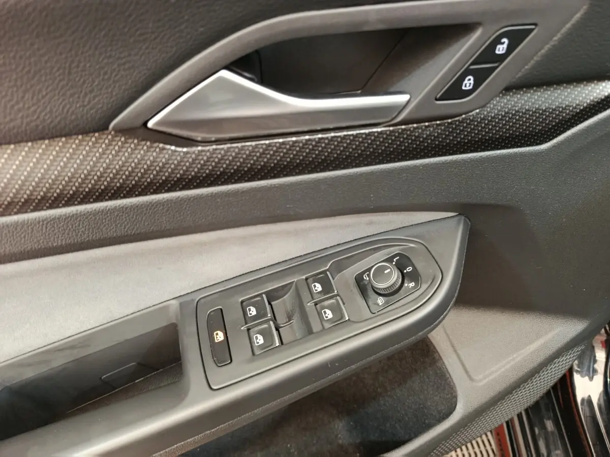 Détail de la commande des vitres et rétroviseurs côté conducteur de la Volkswagen Golf 1.5 eTSI noire, intérieur noir.