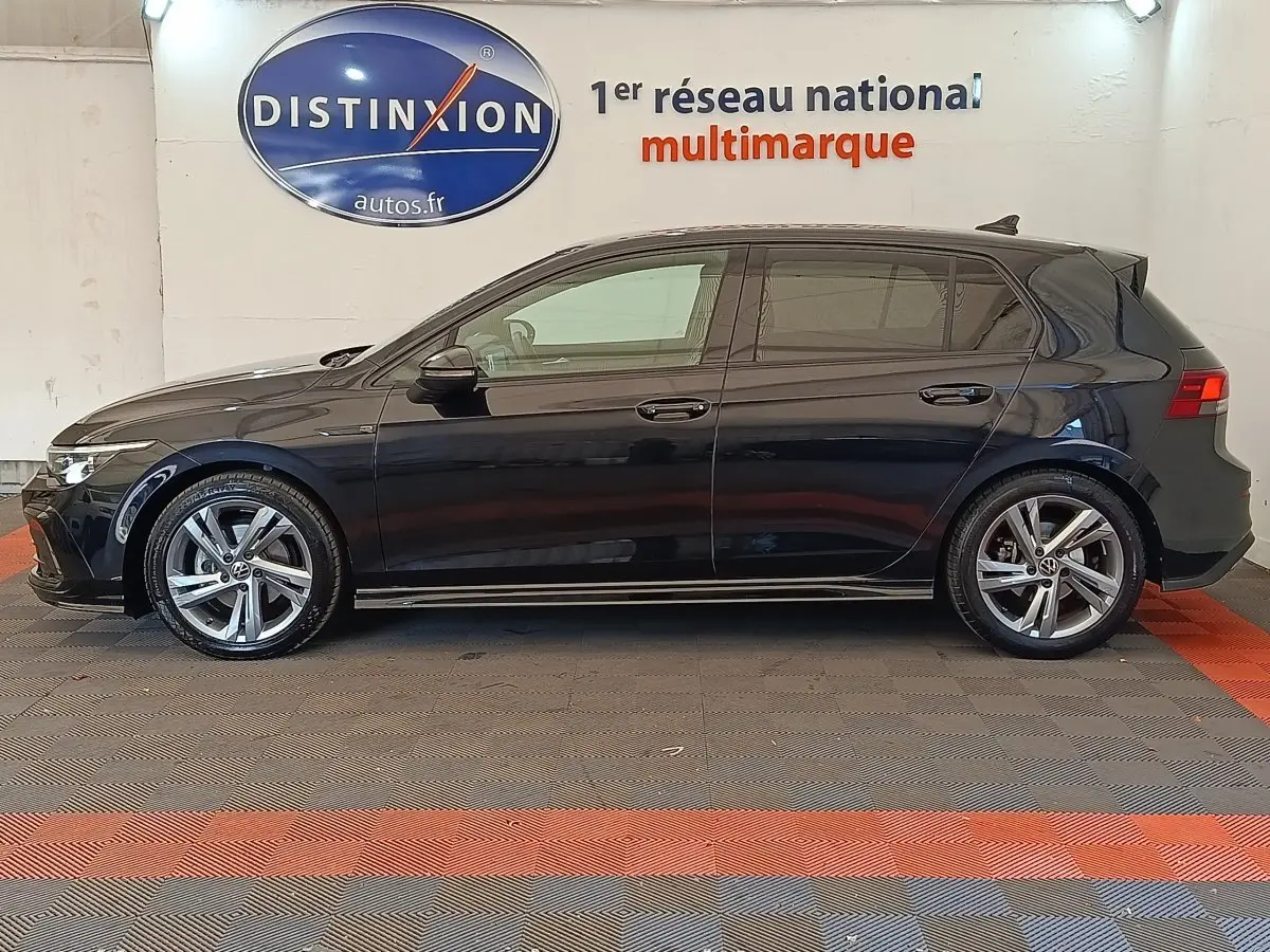 Volkswagen Golf 1.5 eTSI R-Line noire vue de profil côté gauche dans un showroom avec jantes alliage.