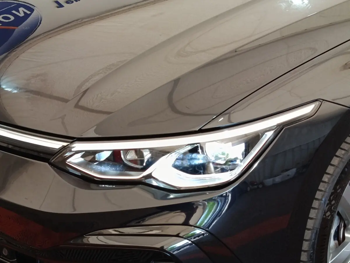 Gros plan sur le phare avant droit d'une Volkswagen Golf 1.5 eTSI noire, mettant en valeur le design LED moderne.