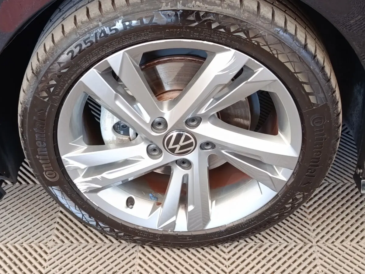 Gros plan sur la jante alliage argentée avec logo Volkswagen au centre d’une Golf noire 1.5 eTSI R-Line.