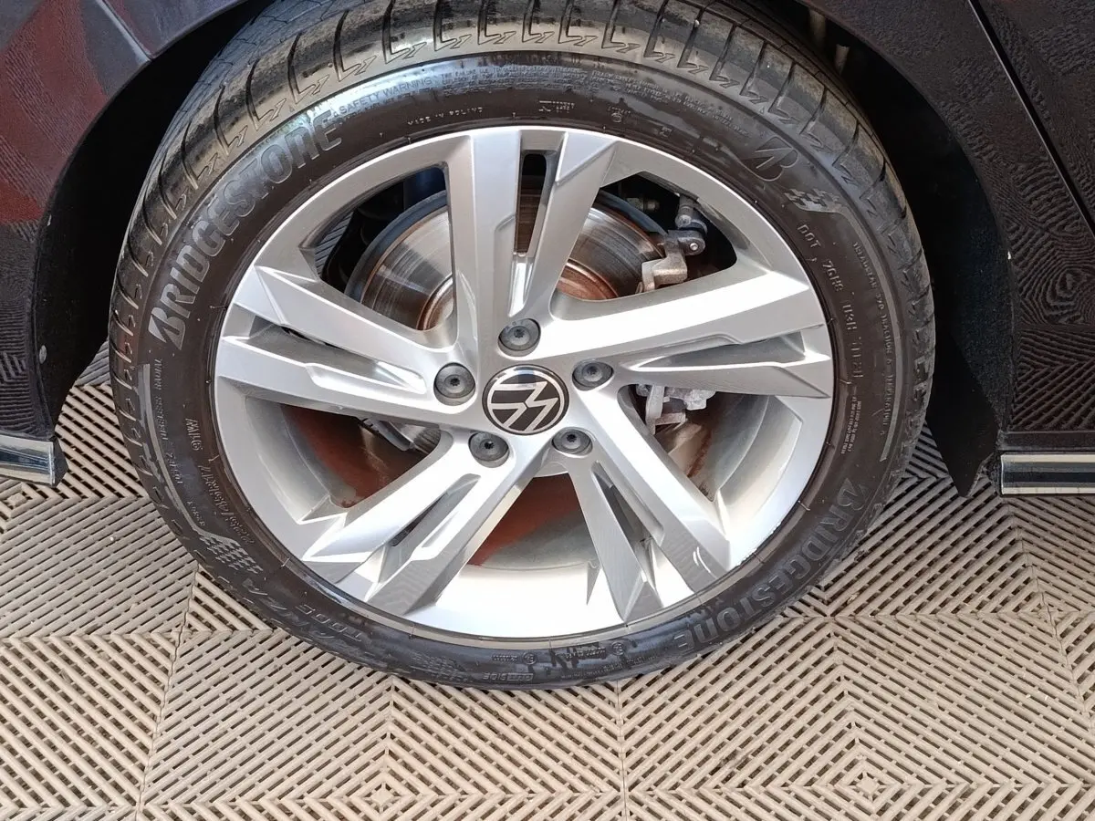 Gros plan sur la roue avant droite de la Volkswagen Golf noire, jante alliage R-Line avec logo VW au centre.
