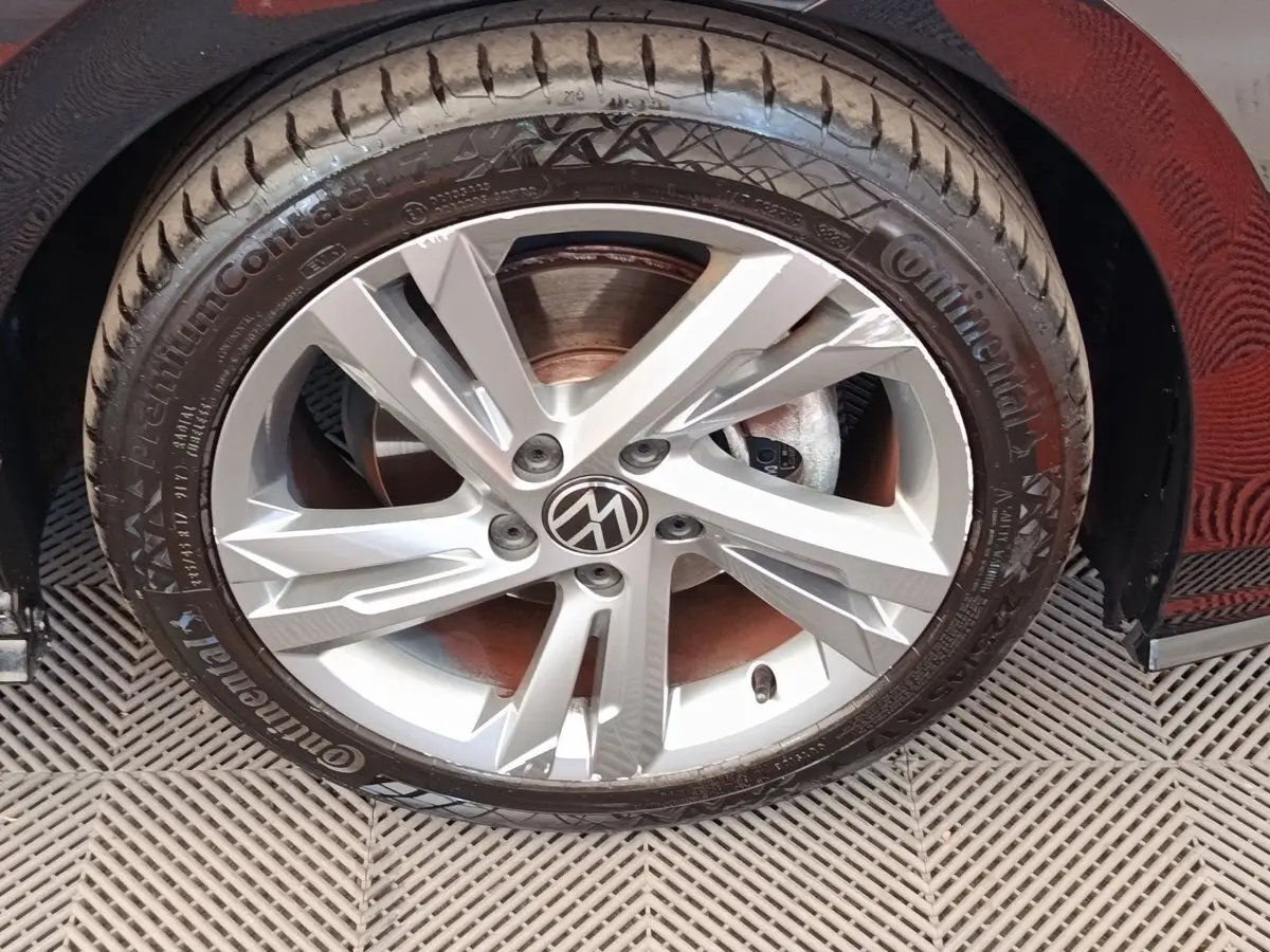 Gros plan sur la roue avant droite d'une Volkswagen Golf noire, avec jante alliage argentée à cinq branches.