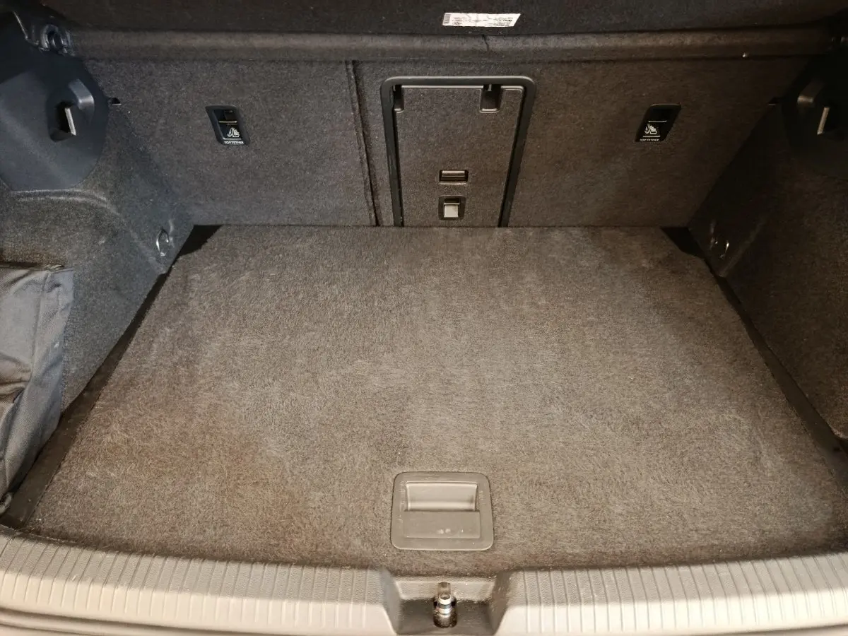 Vue intérieure du coffre de la Volkswagen Golf 1.5 eTSI noir, montrant la banquette arrière rabattable et la trappe à ski.