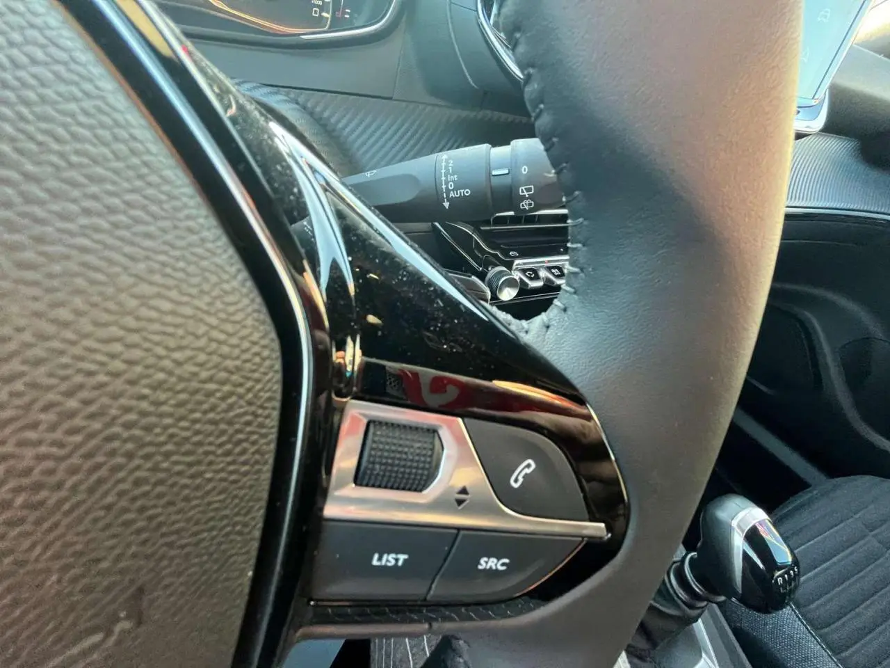 Gros plan sur les commandes au volant côté gauche du Peugeot 2008 2024, avec levier de vitesses manuel visible.