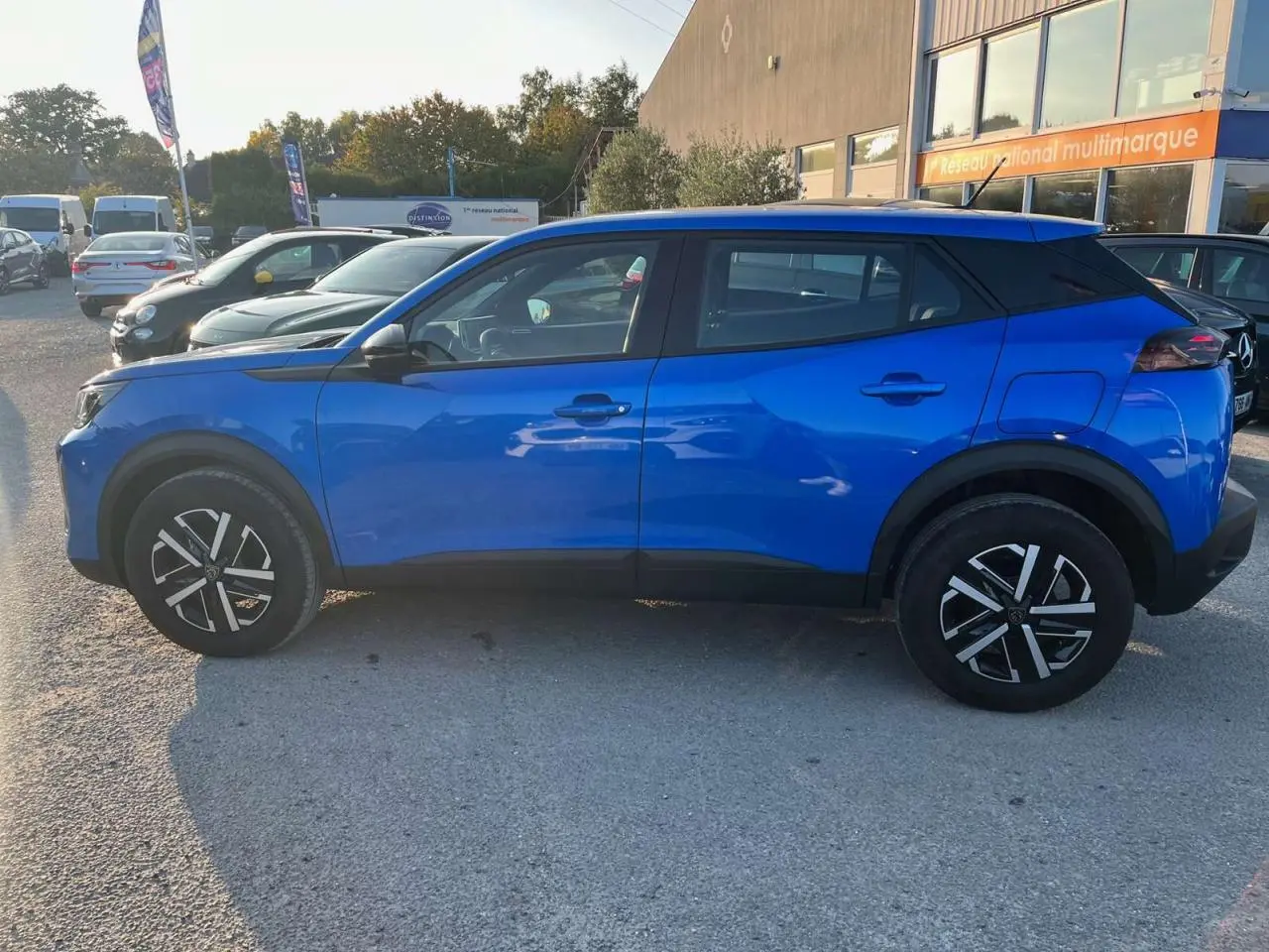Profil côté gauche d'un Peugeot 2008 2024 bleu Vertigo Métal avec jantes noires et toit noir contrasté.