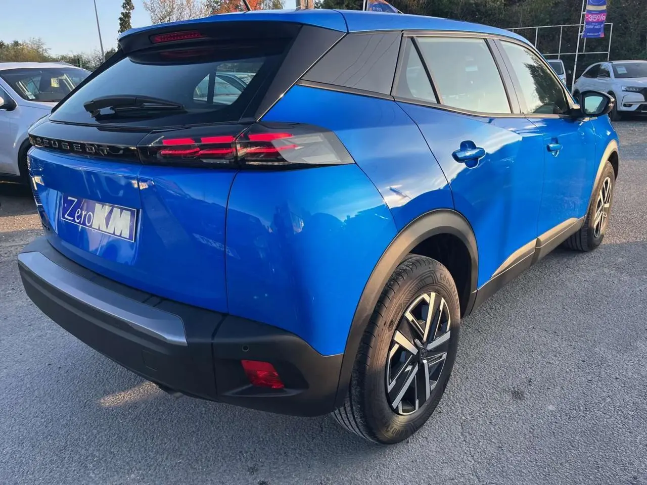 Vue 3/4 arrière droite d'un Peugeot 2008 2024 bleu Vertigo Metal avec toit noir et jantes alliage distinctives.