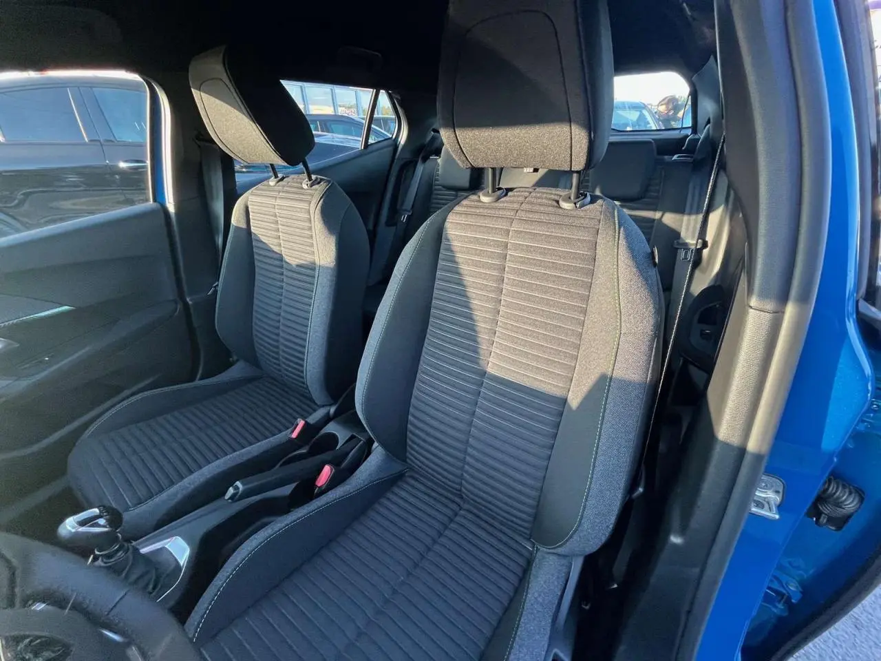 Intérieur du Peugeot 2008 2024 bleu Vertigo Metal, vue côté droit sur les sièges avant en tissu gris et la boîte manuelle.