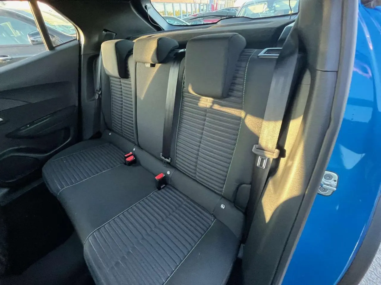 Vue intérieure sur la banquette arrière noire du Peugeot 2008 2024, avec portière bleu Vertigo Metal ouverte côté droit.