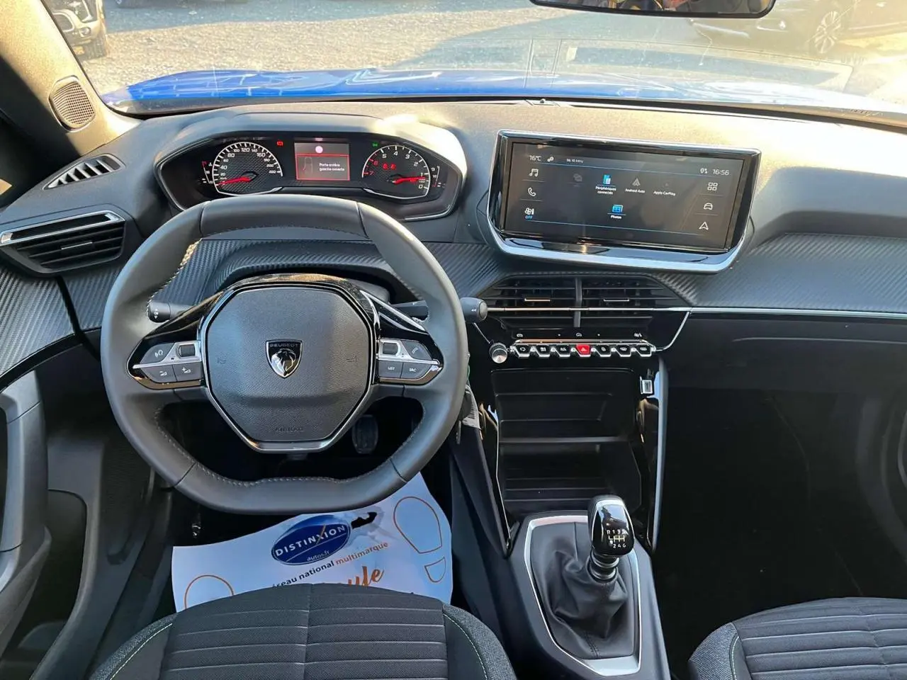 Vue intérieure du tableau de bord du Peugeot 2008 2024 avec volant compact, écran tactile et levier de vitesse manuel.