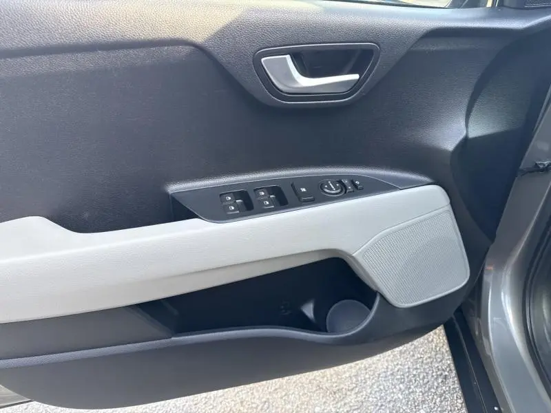 Vue rapprochée de la porte avant gauche du Kia Stonic brun Sienne, montrant les commandes électriques et la poignée intérieure grise.