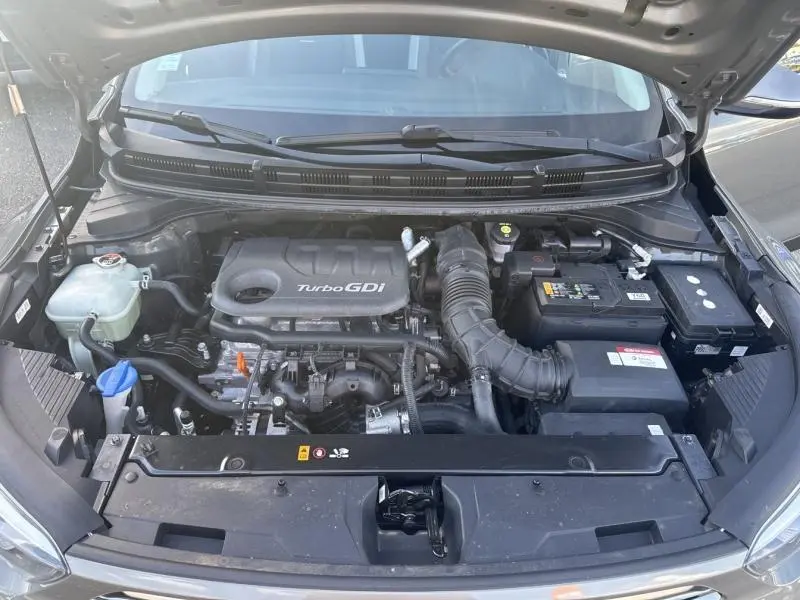 Vue rapprochée du moteur Turbo GDi sous le capot ouvert d'une KIA Stonic brun Sienne de 2019.