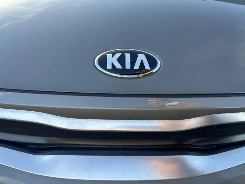 Gros plan sur la calandre et le logo KIA d'une KIA Stonic brun sienne vue de face.
