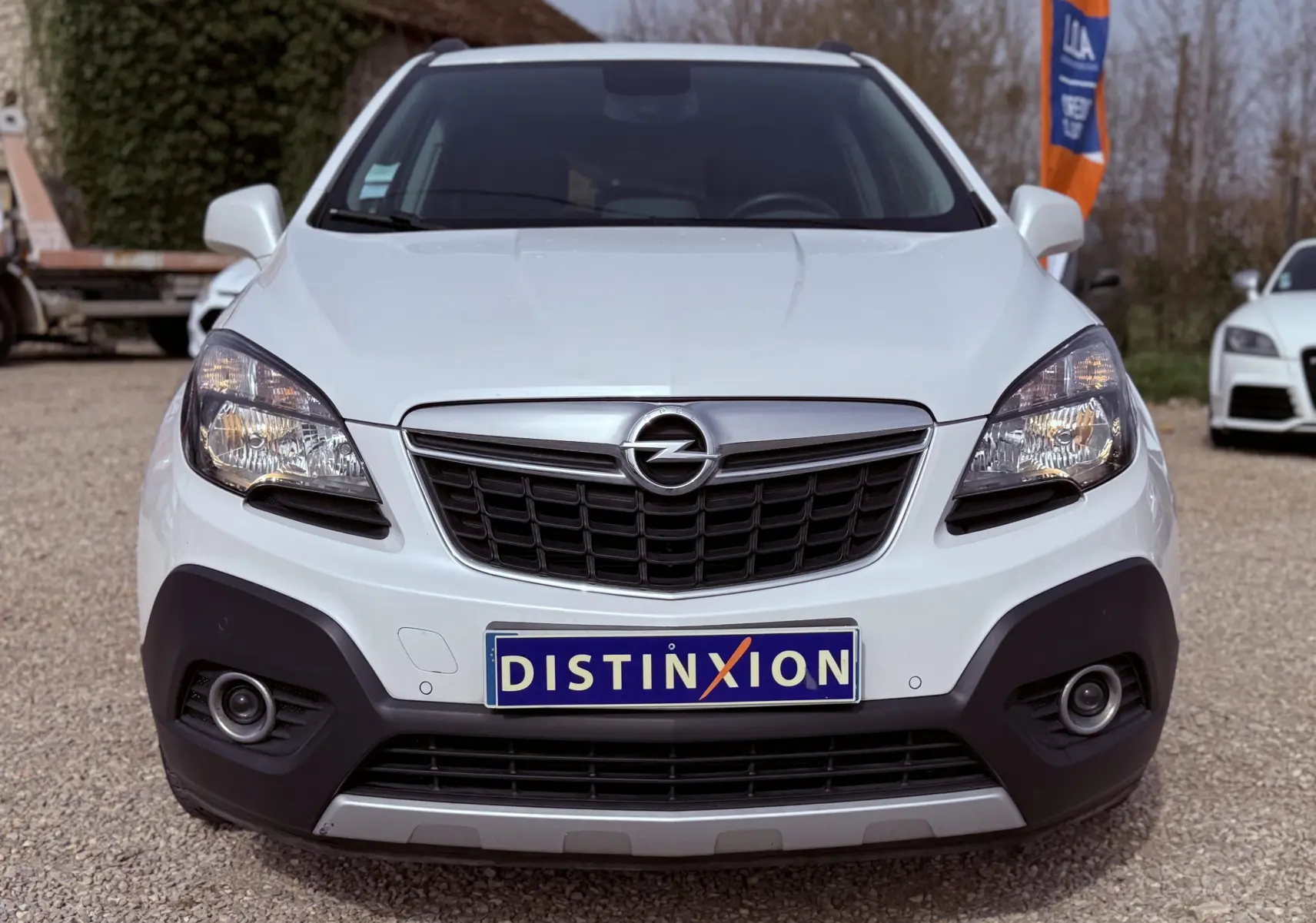 Vue de face d'un Opel Mokka X blanc avec calandre noire et plaque d'immatriculation Distinxion visible.