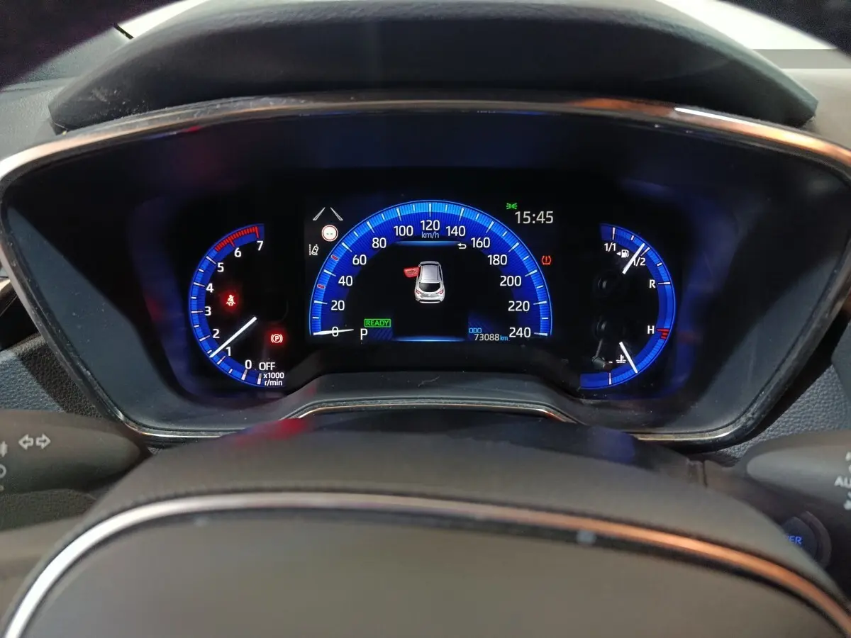 Vue rapprochée du combiné d'instruments numérique bleu de la Toyota Corolla hybride 2022, affichant 73 088 km.