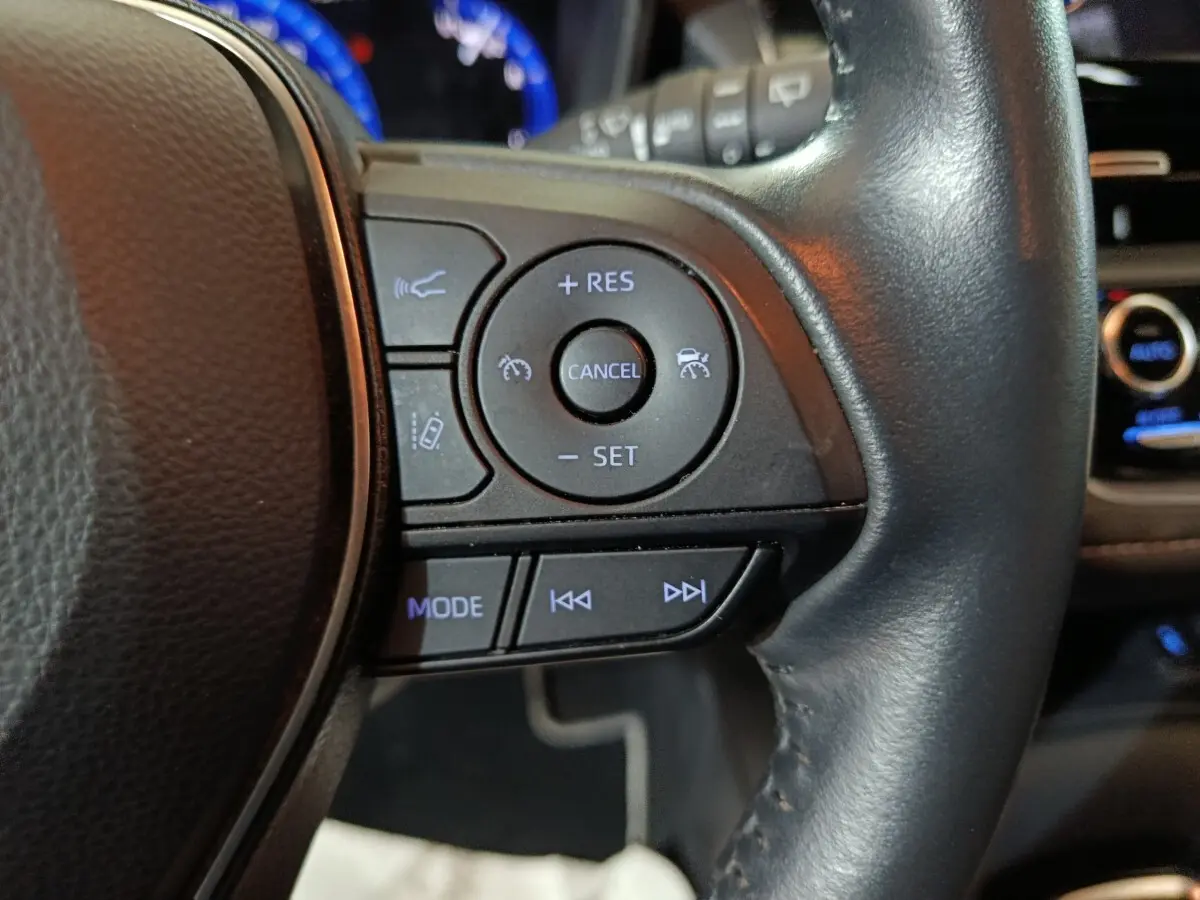 Gros plan sur les commandes du volant cuir noir de la Toyota Corolla hybride 2022, côté droit.