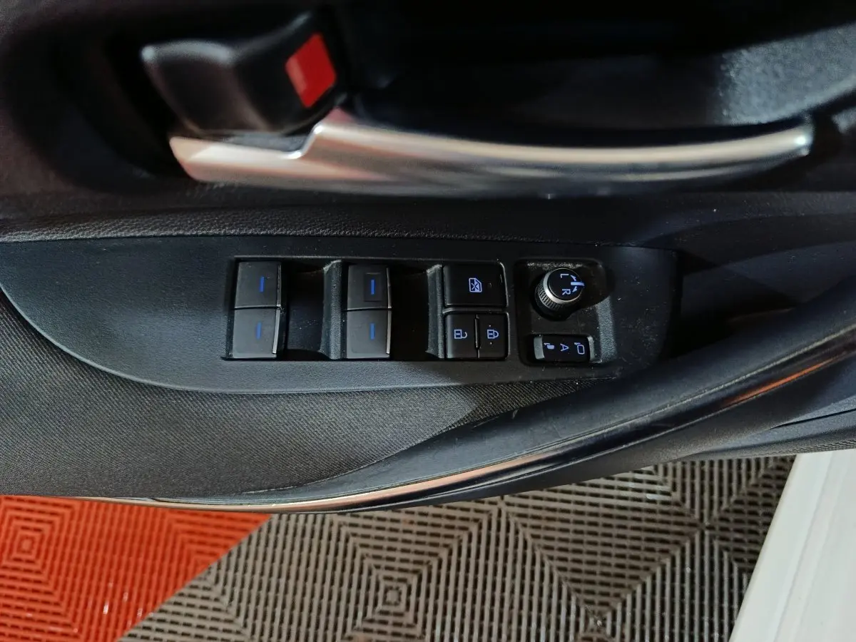 Gros plan sur les commandes des vitres et rétroviseurs côté conducteur de la Toyota Corolla hybride blanche 2022.