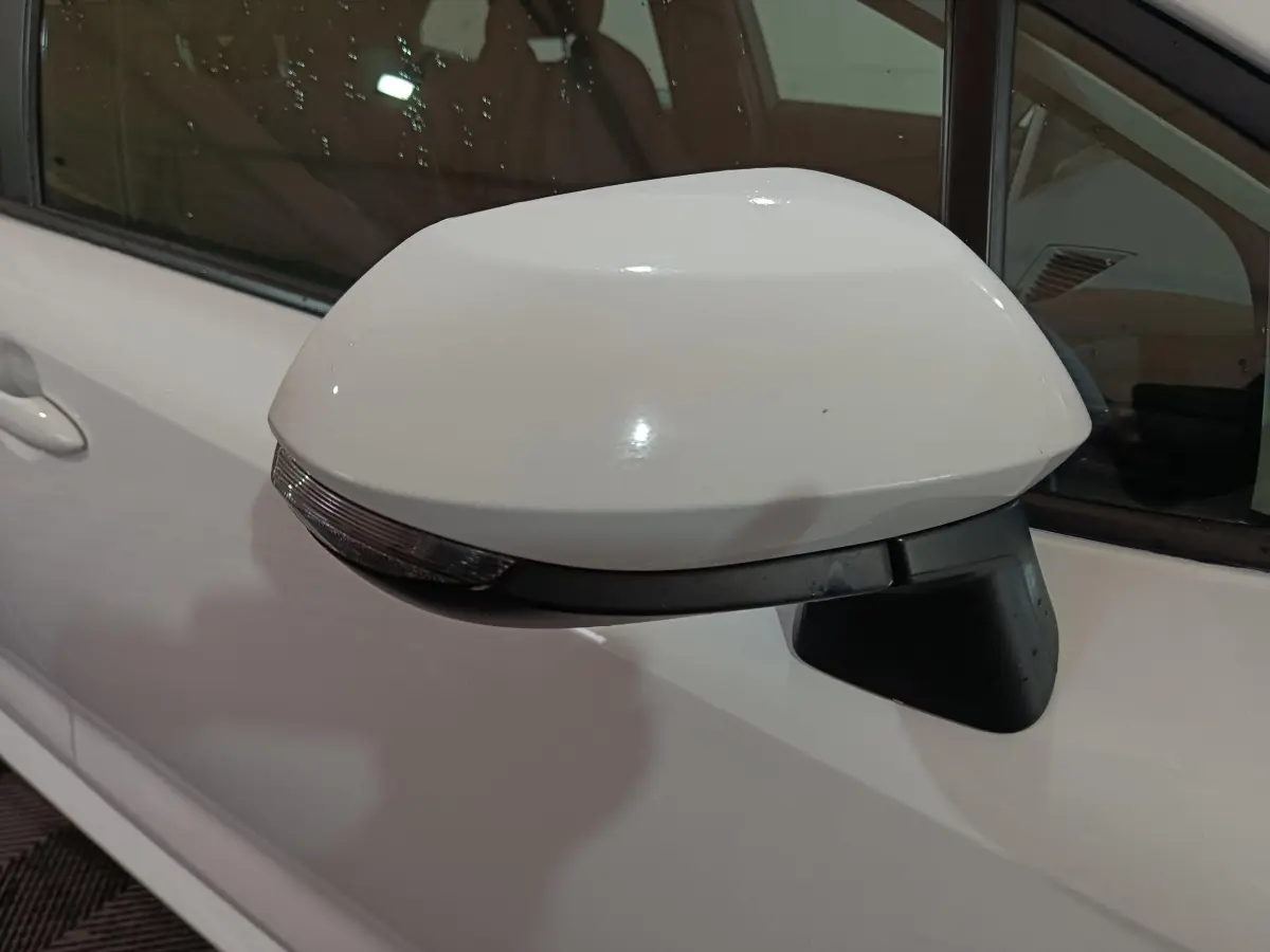 Rétroviseur électrique blanc côté gauche de la Toyota Corolla hybride 2022, avec clignotant intégré.