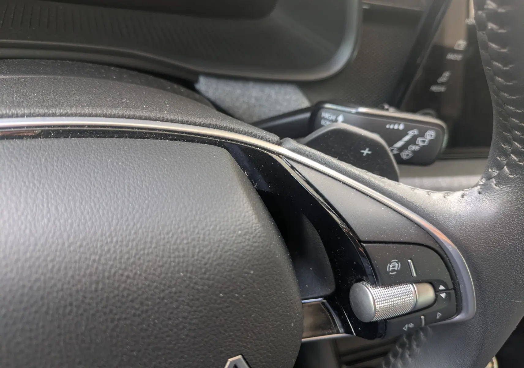 Gros plan sur le volant noir de la Skoda Scala gris reflex, avec molette de réglage et palettes de vitesse visibles.