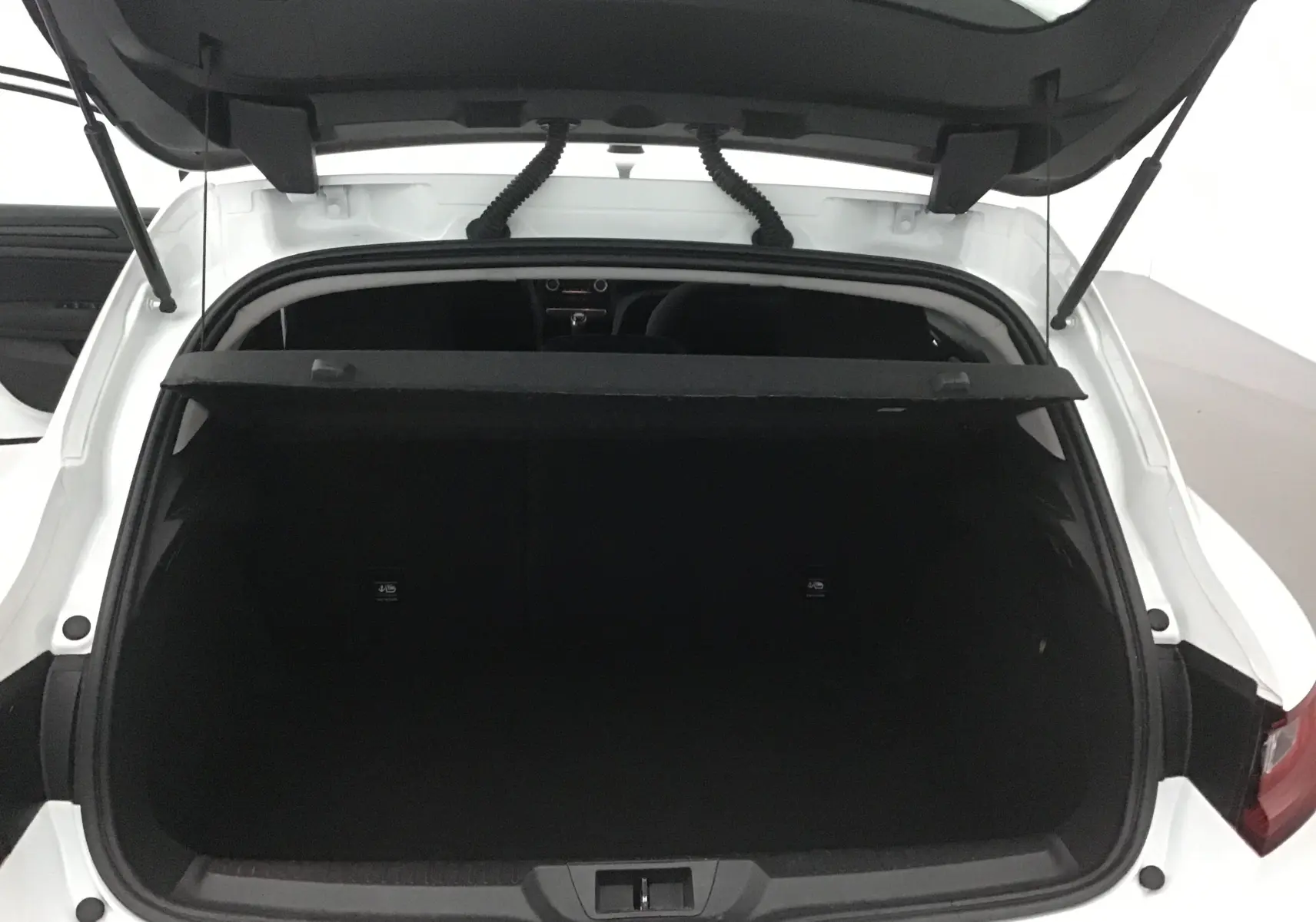Coffre ouvert d'une Renault Mégane IV berline blanche, vue arrière montrant l'espace de chargement vide.