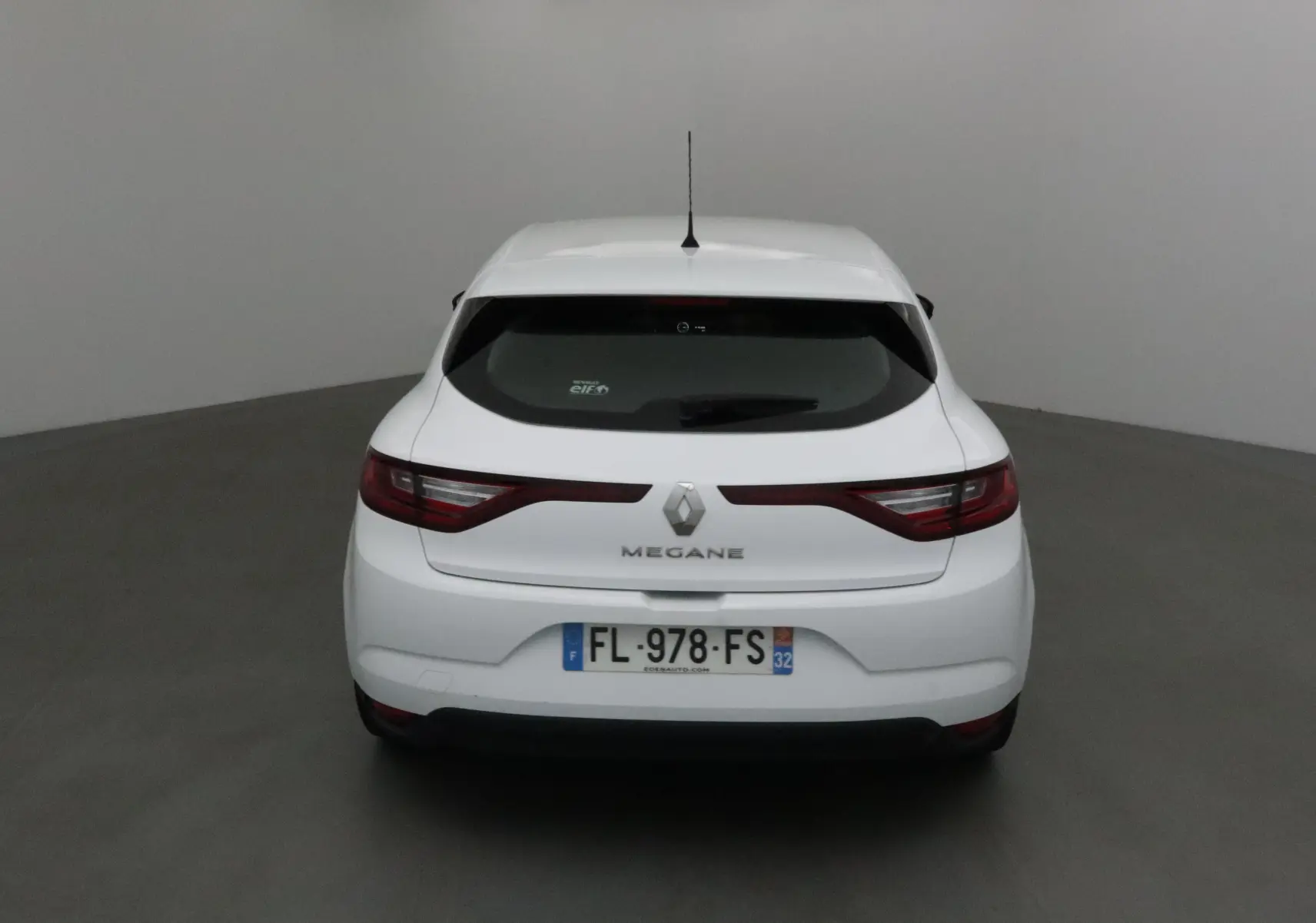 Vue arrière d'une Renault Mégane IV berline blanche, avec feux allongés et plaque d'immatriculation française visible.