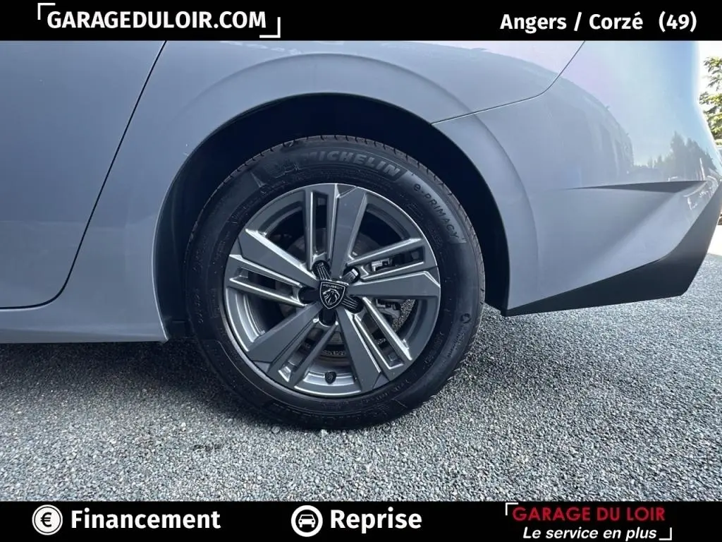 Gros plan sur la roue arrière droite d'une Peugeot 308 gris clair 2023 avec jante alliage au design moderne.