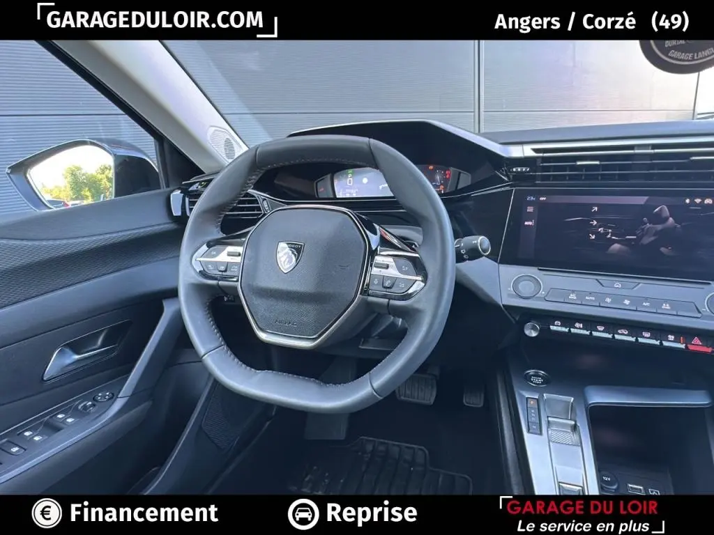 Vue intérieure centrée sur le volant cuir et tableau de bord numérique de la Peugeot 308 gris clair 2023.